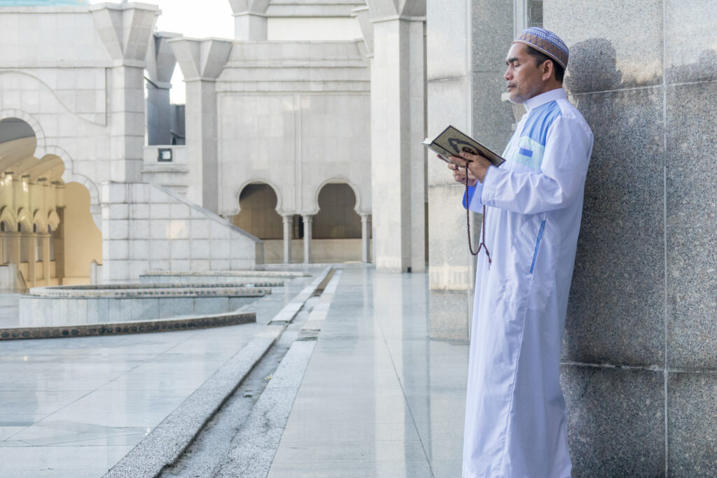 UMRAH IN RAMADAN : REWARDS, TIPS & BEST TRAVEL GUIDE 2025 1 side view man using mobile phone building